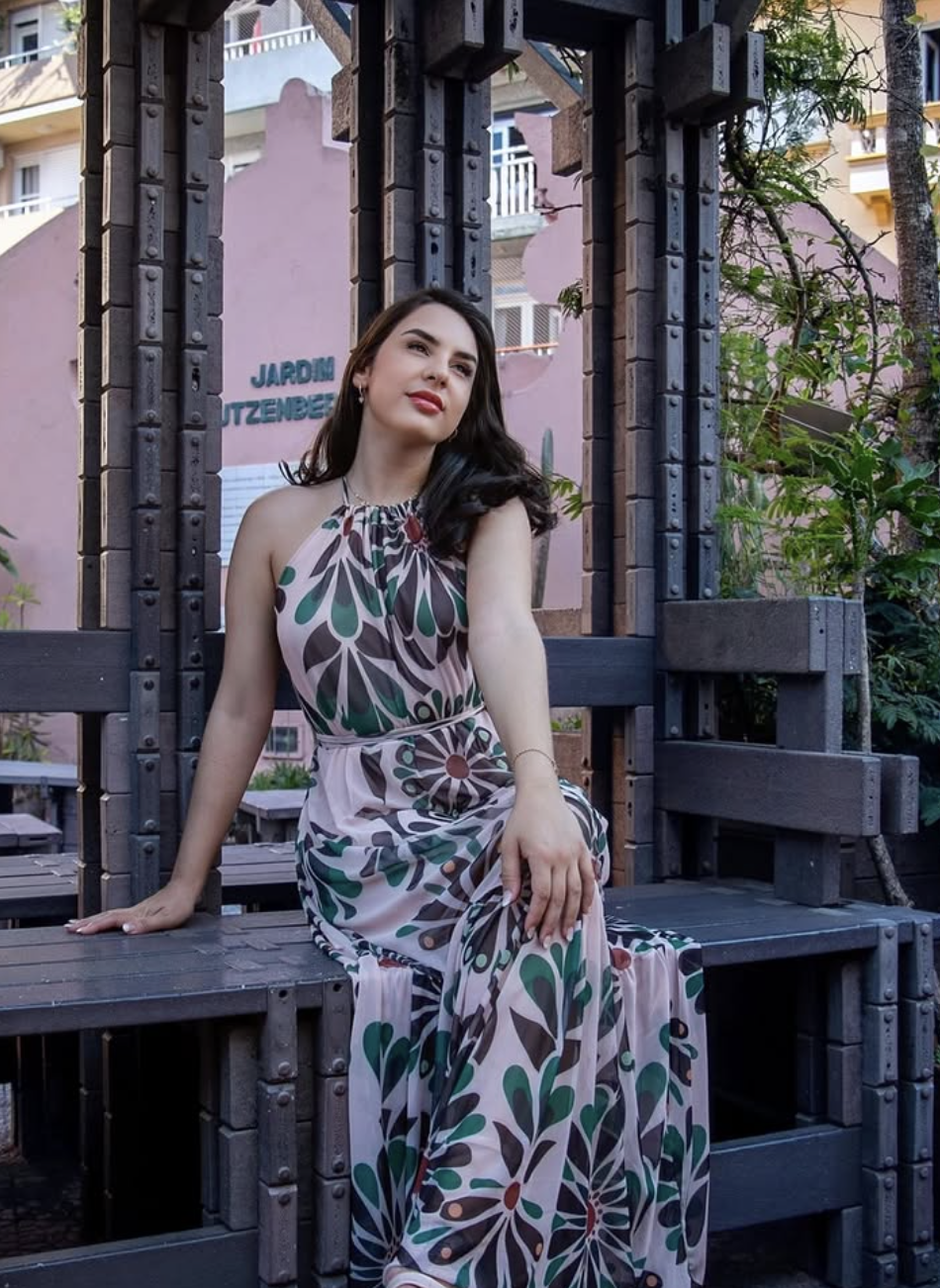 Mariana em vestido estampado sentada em banco de madeira